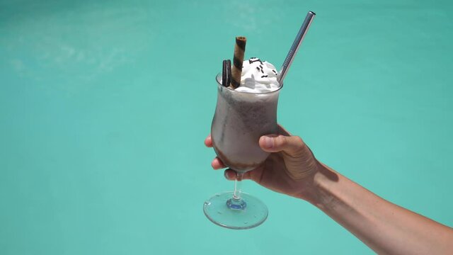 Close up of vegan chocolate milkshake with whipped cream decorated with Oreo cookies. Sustainable metal straw. 