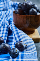 Garden plums in a bowl on a marble background with tablecloth