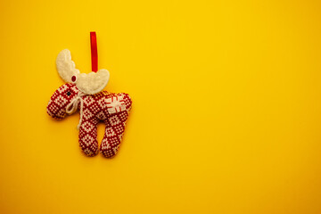 Toy, knitted red deer on a yellow background. Christmas toy for the holiday. High quality photo