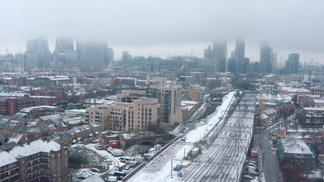 Dolly back aerial drone shot of Snow covering Central London and train tracks