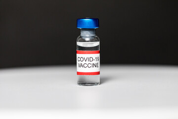 Vial with covid-19 vaccine on black background