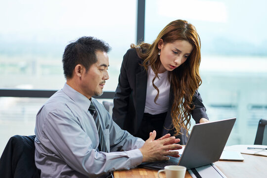 two asian business people mid adult man and young woman working together in office