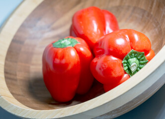 Bamboo bowl of three, fresh, red, bell peppers, macro 