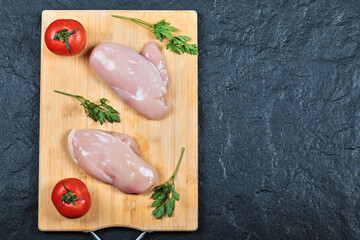 Raw chicken fillets on wooden board with fresh vegetables