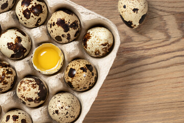 Quail eggs in cardboard packaging on a wooden table close-up, copy space,, flatlay