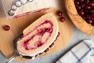Homemade biscuit sweet roll with cranberries and cream on gray table, top view, flat lay