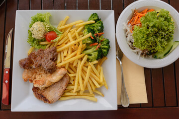 Rustic Meat Dish With French Fries And Salad On The Table
