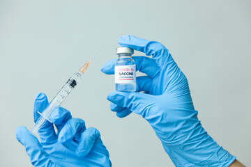 COVID-19 coronavirus vaccine concept. Doctor in medical gloves with a coronavirus vaccine bottle and syringe in his hands.