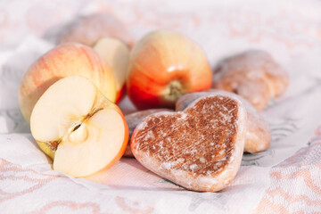 Glazed gingerbread cookies in the shape of heart.Picnic in nature, light snack with apples and cookies.Selective focus.