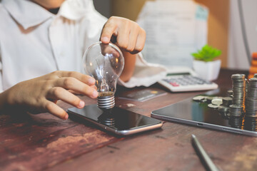 Business men display operational plans, analyze, process creative business strategies, symbolized by a light bulb that conveys the concept of energy, investment, finance.	