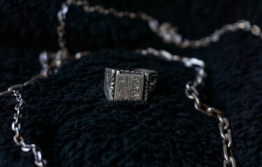 silver ring with black background surrounded by silver chains.