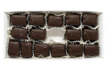 Isolated on a white background, a rectangle box of chocolate truffle pieces with one missing in the...