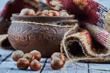 A bowl of hazelnuts on blue wooden table with carved rug
