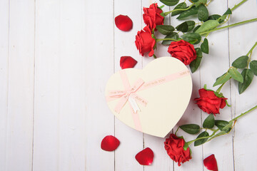 Valentine's Day. Red rose flower and gift box on wood background.