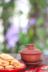 Vertical composition: a plate of spring rolls, a cup of tea and a red envelope