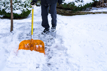 Orange shovel with snow during winter cleaning in the hands of a man