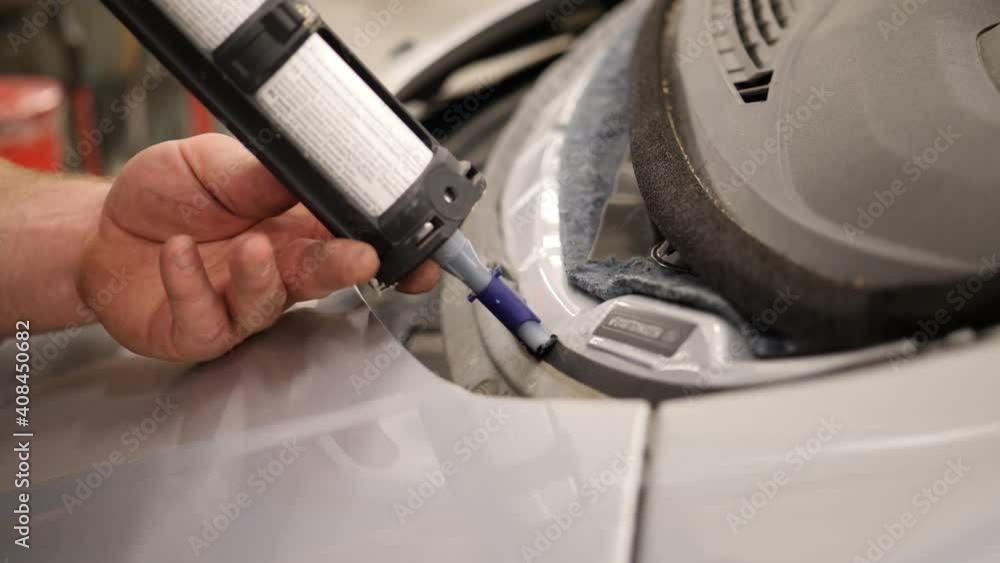 Poster using a glue gun to apply glue to replace a front windshield on a vehicle - isolated