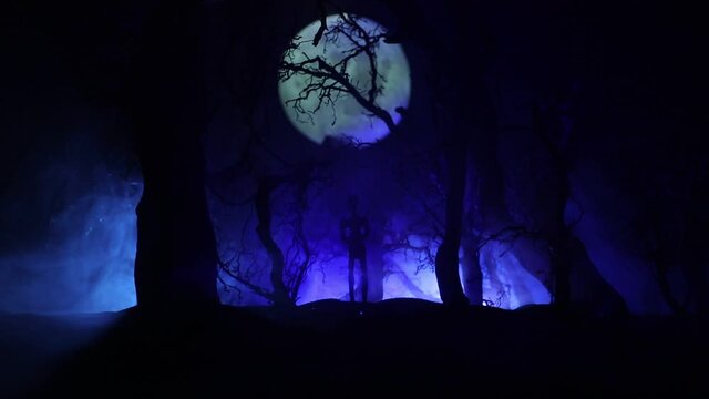 bloodthirsty zombies attacking concept. Silhouette of scary zombie walking in the dead forest at night. Creative table decorations. Selective focus