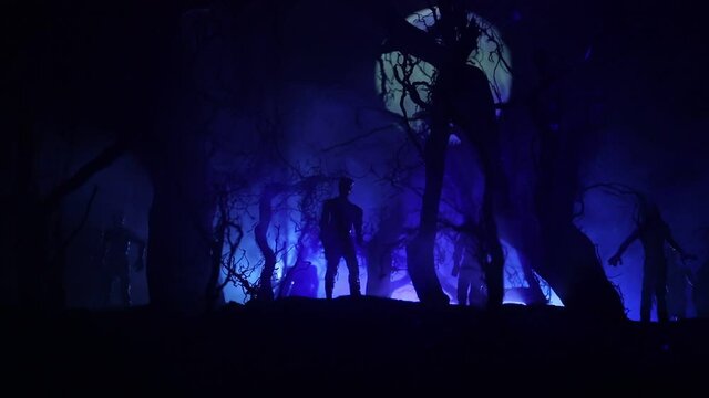 bloodthirsty zombies attacking concept. Silhouette of scary zombie walking in the dead forest at night. Creative table decorations. Selective focus