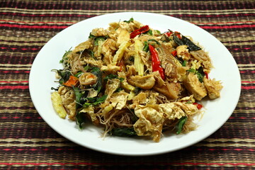 Fried and stirred spicy rice noodle with tofu sheet, baby corn and basil serving on the plate. Famous vegetarian menu in Asia restaurant. 