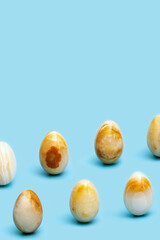 Pattern from Easter eggs from Natural gemstone onyx on blue paper. Trendy spring holiday arrangement.