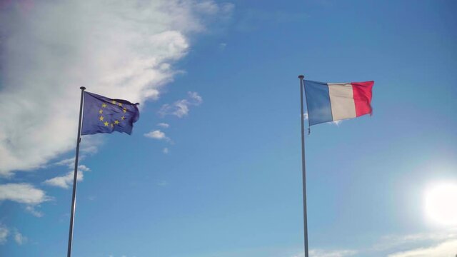 EU and French flags waving in strong wind on a blue and cloudy sky, symbol of the alliance with the European Union