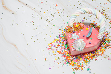 Pink heart shape cake on a white marble background with a lot of small colorful candies. Valentine day. About love. copy space. High quality photo
