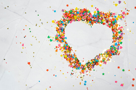 Heart shape made from small colorful candies on a white marble background. Valentine day. About love. High quality photo