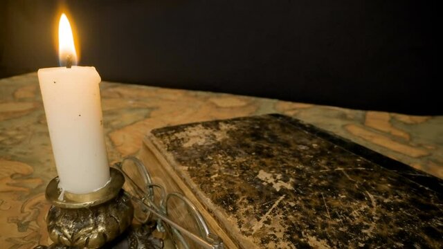 The thick old book and the telescope spotting scope on top of the map with the candlestick on the side