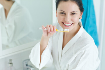 Portrait of a beautiful woman brushing her teeth in the bathroom. High quality photo