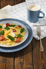 Farfalle with mozzarella cherry tomatoes and spinach in a rustic style.