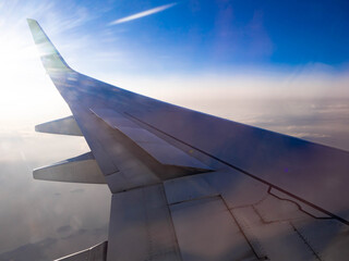 Fototapeta na wymiar 夜明けの飛行場を離陸し、朝日を浴びて飛行する飛行機に搭乗して窓から撮影した翼