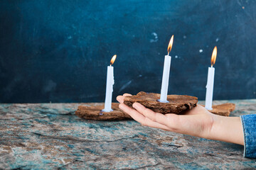 Woman holding burning candles on marble table