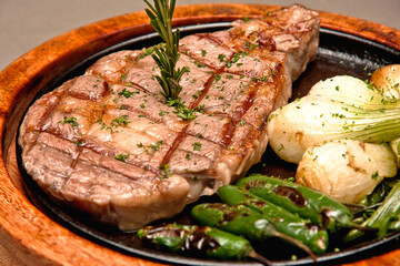 Grilled beef steak with serrano peppers and roasted onions Delicious beef steak on gray background, ribeye