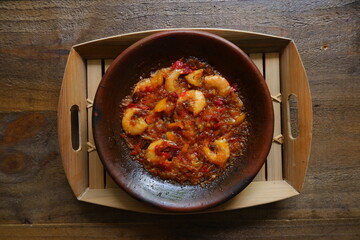 a plate of prawn cooked in sambal in an earhenware plate named gami udang is an Indonesian cuisine from Bontang, Borneo.