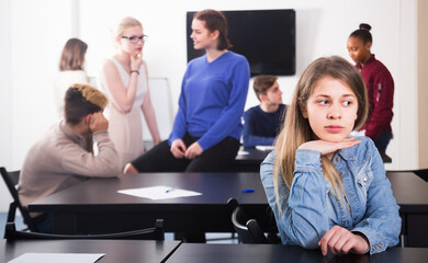 upset female student feeling uncomfortable at break between classes sits by the table