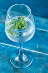 A glass of juice with mint on blue background
