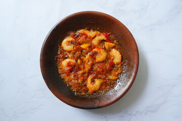 a plate of prawn cooked in sambal in an earhenware plate named gami udang is an Indonesian cuisine from Bontang, Borneo.