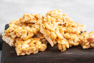 Peanuts in sugar glazed, oriental sweetness of brittle. Kozinaks are broken into pieces on a wooden Board, copy space.