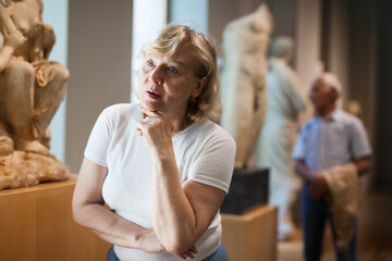 Mature woman visiting exposition of Art Museum with exhibits of antiquity