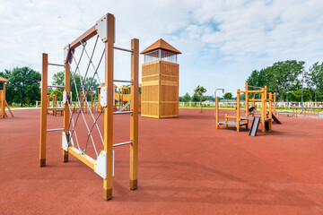 The rope net equipment on a child playground with the natural surface covered by red clay