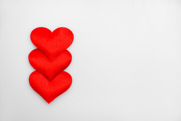 Three textured red hearts on top of each other on a white or gray background: place for text, St. Valentine's Day background, minimalism 
