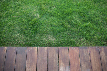 Empty wooden deck with green grass background.