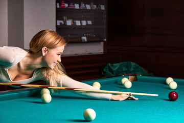 woman playing snooker, she is aiming to shoot the snooker ball, holding hands on snooker table....