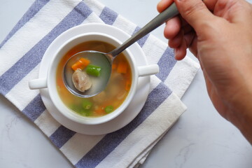 vegetable soup in a spoon from a bowl on a white background