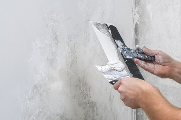 A male worker spreads the putty mixture and flattens the wall.