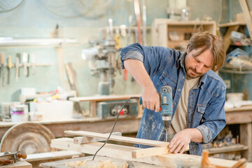 Worker using screwdriver at a workshop. Empty space for text