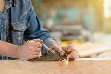 Close up mans hands planing wood in a workshop. Empty space for text