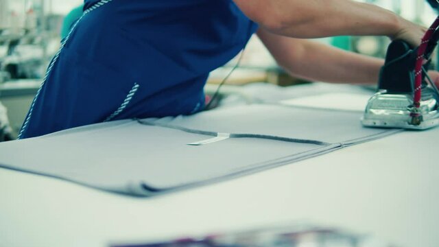 Textile worker is ironing a clothing item