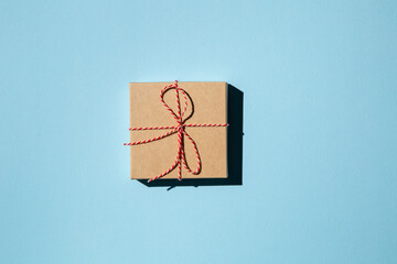 Fototapeta na wymiar Gift box or present wrapped in craft paper on a blue background. Holiday present.
